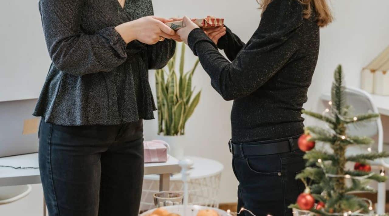 Woman learning how to politely decline gifts while returning a wrapped Christmas present to the giver