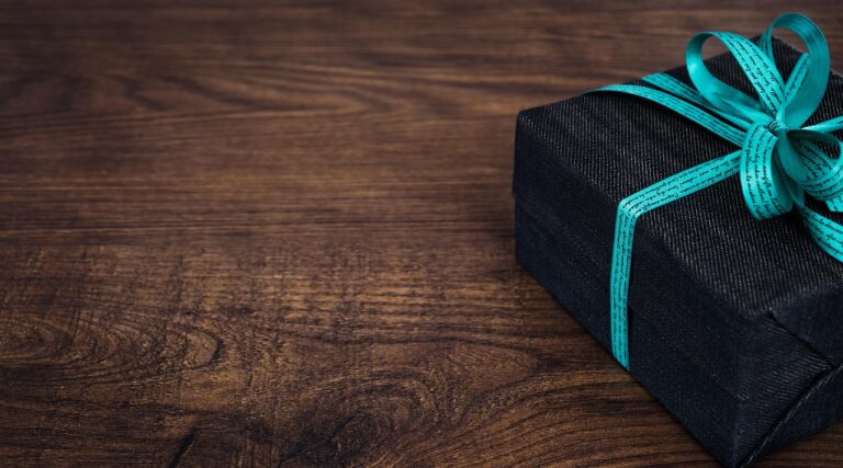 Meaningful Gifts on a Budget: Showing Care Without Overspending – a thoughtfully wrapped gift with a turquoise ribbon on a wooden table
